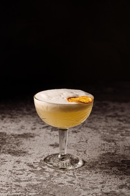 Orange alkoholischer Cocktail mit Zitrusfrüchten auf schwarzem Hintergrund