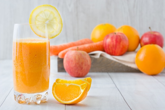 Orange, Apfel und Karotten Smoothie auf weißem Holztisch