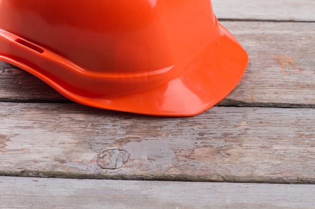 Orange Arbeiterhelm auf dem alten Holztisch. Konstrukteurskappe schließen.