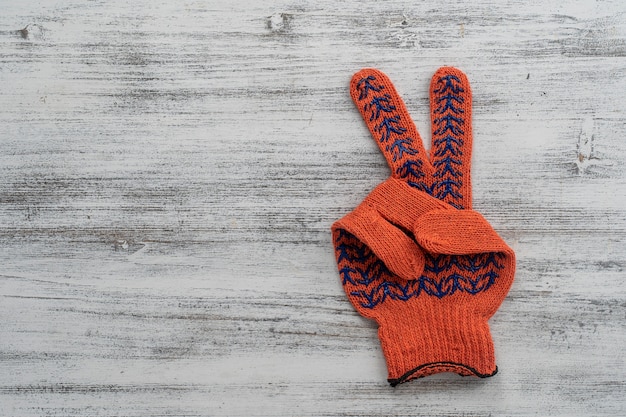 Orange Bauhandschuhe zeigt Siegeszeichen auf weißem hölzernem Hintergrund, Kopienraum