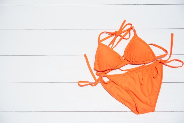 Orange Bikini steht auf einem Bretterboden - Sommer und Reise cocept still.