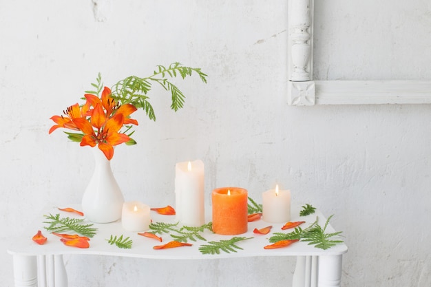 Orange Blumen und Kerzen auf weißem Hintergrund