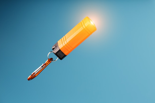 Orange führte Taschenlampe mit einem Karabiner auf einem blauen Hintergrund. LED leuchtet im Flug.