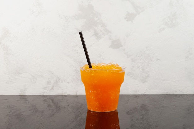 Orange Granizado im Einweg-Plastikbecher. Slushie-Getränk. Eisgetränk. Süße Zitrusfrüchte Geschabtes Eis.