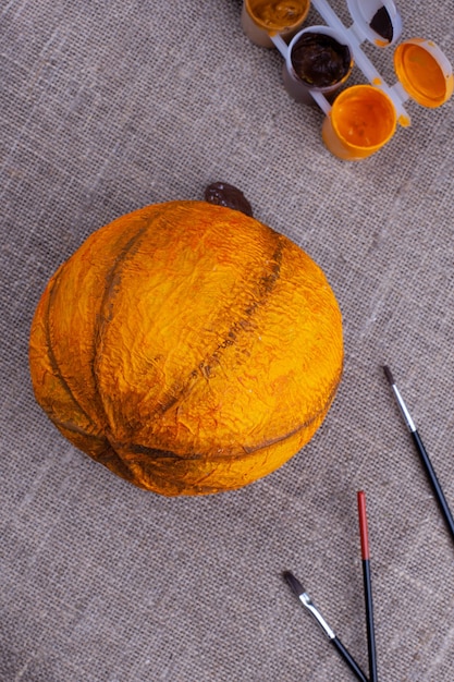 orange hausgemachter Kürbis aus Pappmaché, Pinsel, Farbe auf Sackleinen, Vorbereitung und Feier von Halloween