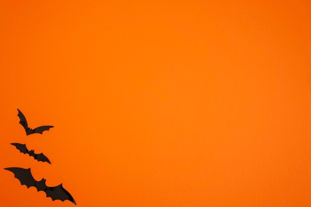 Foto orange hintergrund mit fledermäusen in der unteren linken ecke kopierraum halloween
