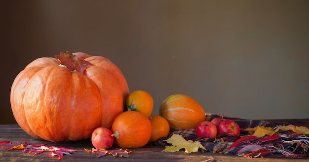 Orange Kürbisse mit Herbstlaub auf Holztisch