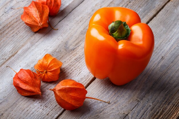 Orange Pfeffer und Physalis auf einem hölzernen Hintergrund