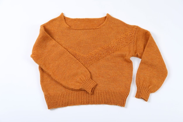 Orange Pullover auf weißem Hintergrund, Ansicht von oben.