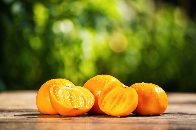 Orange Tomaten auf dem Tisch auf einem grünen Hintergrund