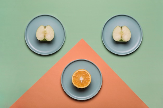 Foto orange und apfel auf flachen tellern auf einem farbigen grün-orange hintergrund. konzept der gesunden ernährung und vitamine.