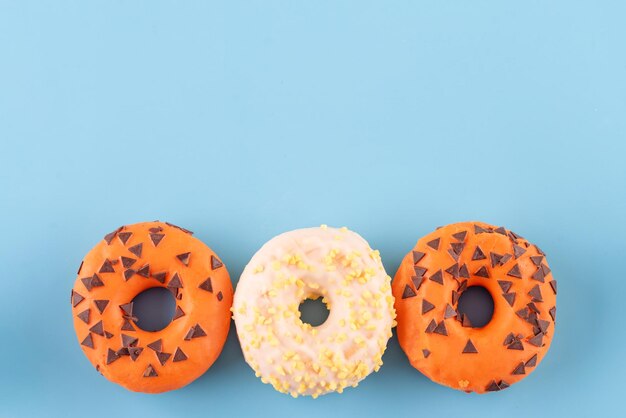 Orange und gelb bestreute Donuts auf blauem Hintergrund Halloween