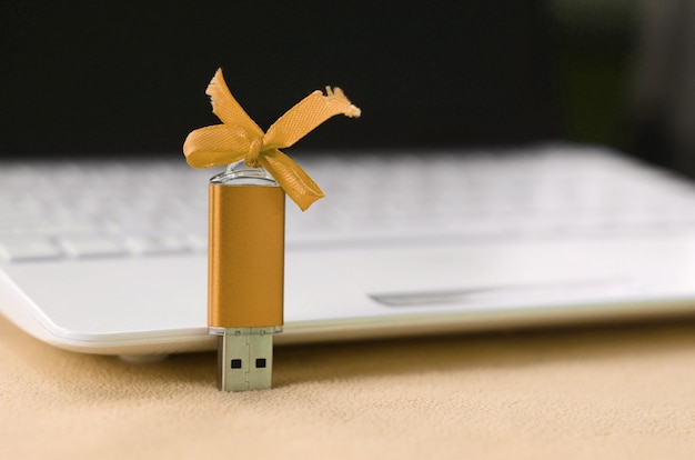 Orange USB-Flash-Speicherkarte mit einem Bogen liegt auf Decke