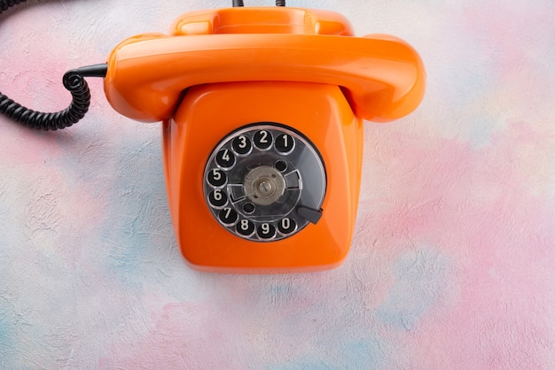 Orange Vintage Telefon auf einem mehrfarbigen Tisch - Draufsicht