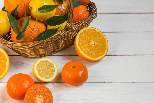 Orange Zitronenzitrusfrüchte in einem Korb und in einem Saft auf einem hellen Hintergrund, gesundes Lebensmittel der Diät