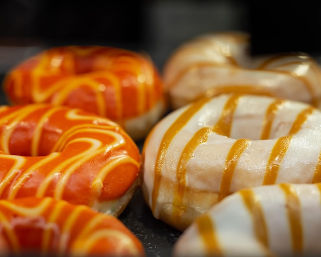 Orange Zuckerguss und weißer Zuckerguss auf Donuts mit Karamellabdeckung Nahaufnahme Restaurant süße Menüanzeige