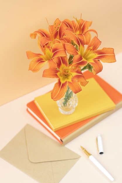 Orange Zusammensetzung mit Blumen und Notizbüchern