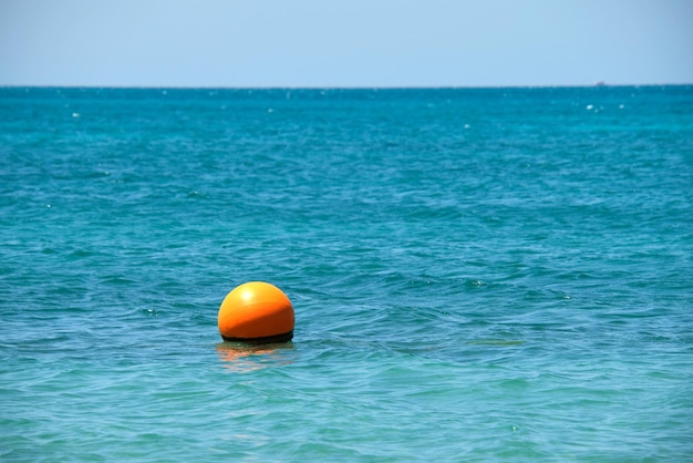 Orangefarbene Boje, die auf Meeresoberflächenwellen schwimmt. Sicherheitskonzept für das menschliche Leben.