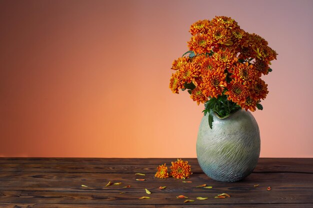 Orangefarbene Chrysanthemen in Vase auf Holzhintergrund