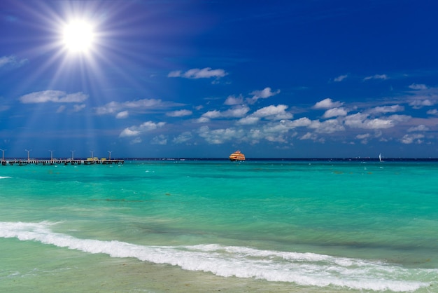 Orangefarbene Fähre im azurblauen Ozean mit schwimmenden Menschen in Playa del Carmen Yukatan Mexiko