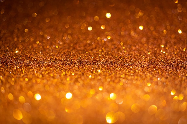 Orangefarbene Glitzerlichter. Glänzendes Funkeln, Bokeh-Effekte, leuchtende Oberfläche. Selektiver Fokus, Weihnachtszusammenfassungs-Hintergrundfoto