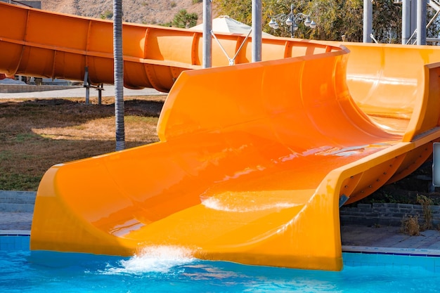 orangefarbene Rohrtunnel, die in einen Pool mit Wasserrutschen, Wasserparkfahrten abgelassen werden