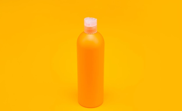 Orangefarbene Shampooflasche auf gelber Hintergrundhygiene