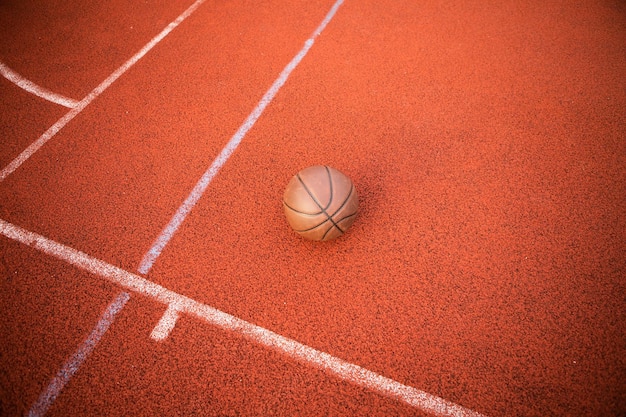 Foto orangefarbener ball der draufsicht für den basketball, der auf dem gummisportplatz liegt. sport roter boden im freien