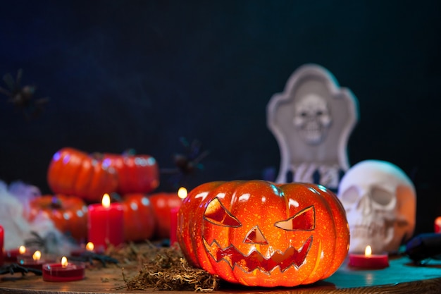 Orangefarbener Kürbis geschnitzt mit einem gruseligen Gesicht für Halloween-Feiern. Furchtsamer Schädel auf Holztisch.