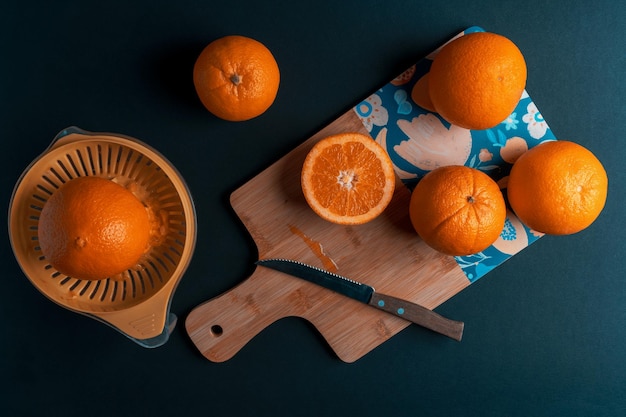 Orangen auf einem Küchenbrett und Entsafter auf dunklem Hintergrund