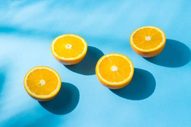 Orangen auf einer blauen Oberfläche unter natürlichem Licht mit Schatten. Hartes Licht. Konzept der Ernährung, gesunde Ernährung, Erholung in den Tropen, Urlaub und Reisen, Vitamine.