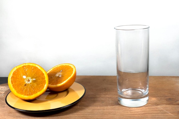 Foto orangen mit glas auf dem tisch gegen die weiße wand