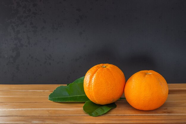 Orangen und grünes Blatt auf Holzboden