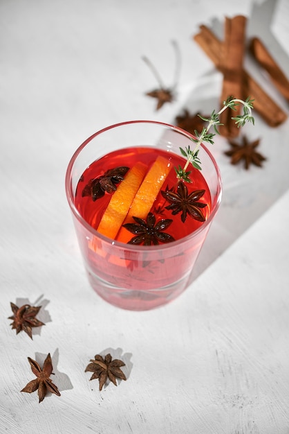 Orangencocktail mit Rum, Schnaps, Birnenscheiben und Thymian auf weißem Tisch, selektiver Fokus