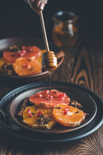 Orangendessert mit Weinhonig oder Ahornsirup und Ingwergewürz verzierte Granatapfelbeeren Wunderbar süßes, reichhaltiges und frisches Essen Dunkler rustikaler Hintergrund, Kopierraum für Ihren Text