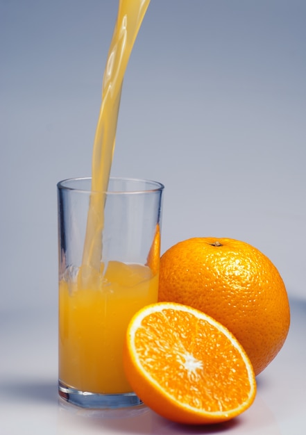 Orangenfrucht mit halber Teil und Saft auf blauem Hintergrund