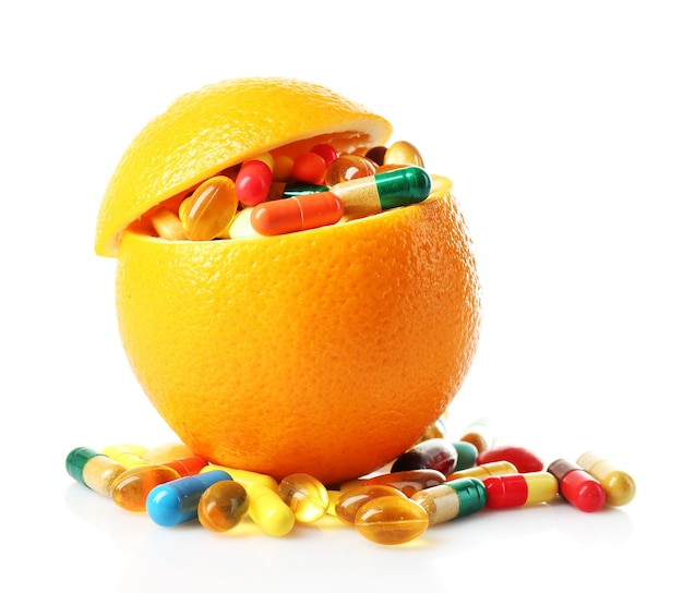 Orangenfrucht und bunte Pillen, lokalisiert auf Weiß