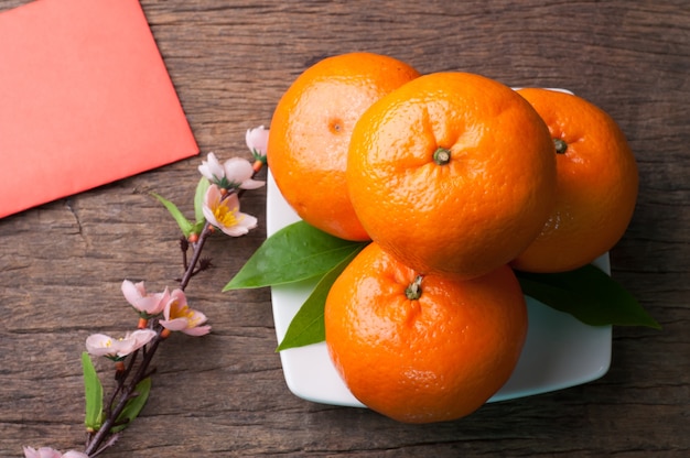 Orangenfrucht und roter Umschlag auf hölzernem Hintergrund