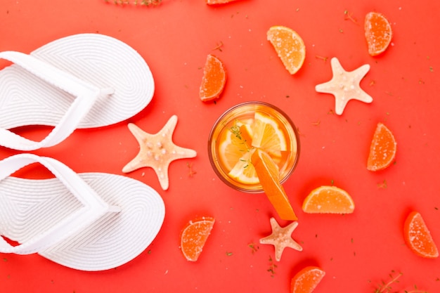 Orangenfruchtcocktail, Entgiftungswasser in der Nähe von weißen Flip-Flops.