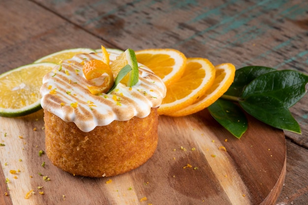 Foto orangenkuchen mit gerösteter weißer sahne auf rustikalem holztisch im bistro, nahaufnahme mit orangenscheiben