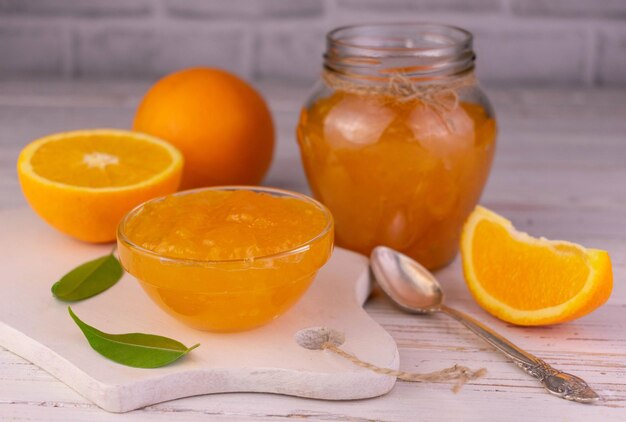 Orangenmarmelade in einer Glasschüssel auf einem weißen Holzbrett