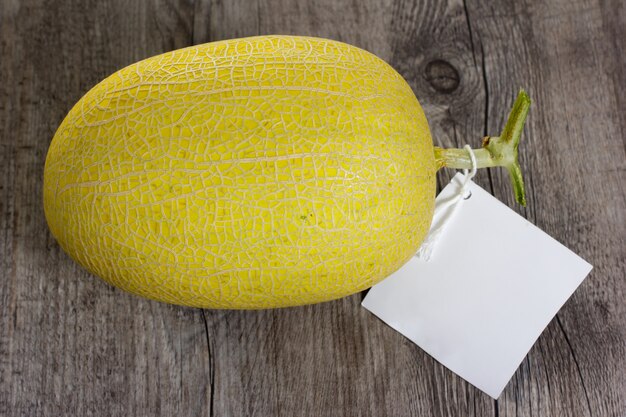 Foto orangenmelone auf holztisch mit weißem etikett.