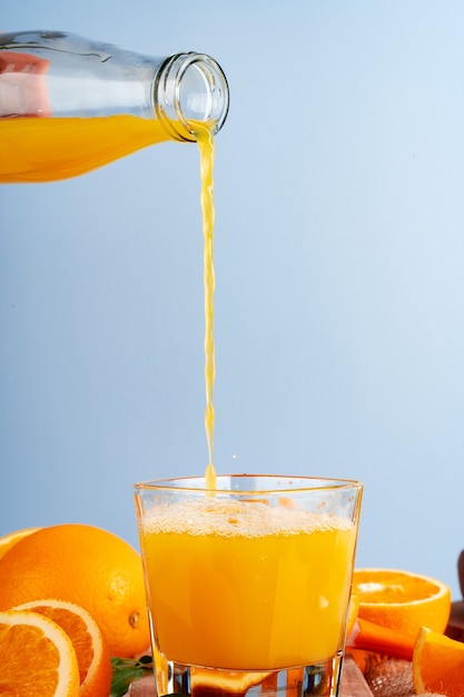 Orangensaft fließt aus der Flasche ins Glas