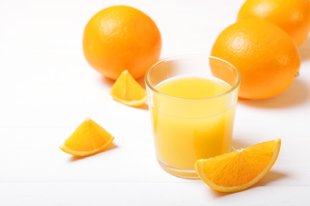 Orangensaft in einem Glas Orangen und Orangenscheiben auf dem Tisch