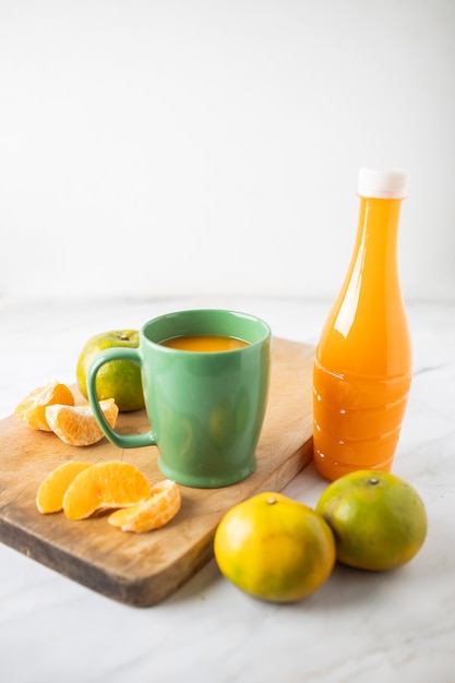 Orangensaft in einer tasse und in einer flasche auf marmor