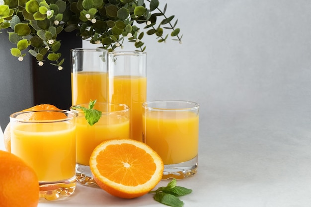 Orangensaft in Gläsern und frischen Orangen auf einem grauen Hintergrundkonzeptfoto