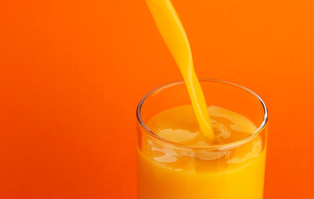 Orangensaft in Glas gießen