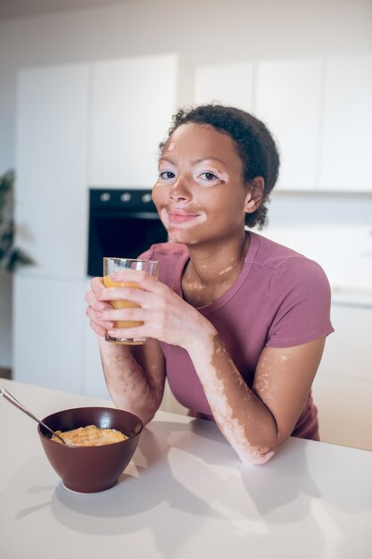 Orangensaft. Junge dunkelhäutige Frau mit einem Glas Orangensaft