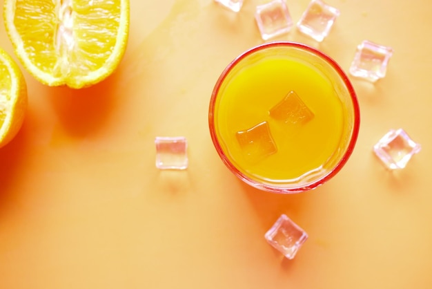 Orangensaft und Eiswürfel im Glas auf farbigem Hintergrund