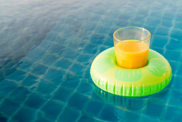 Orangensaftglas mit Schwimmring am Außenpool